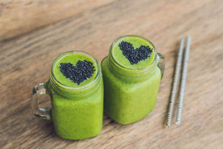 Fresh green smoothie with banana and spinach with heart of sesame seeds. Love for a healthy raw food concept.の写真素材