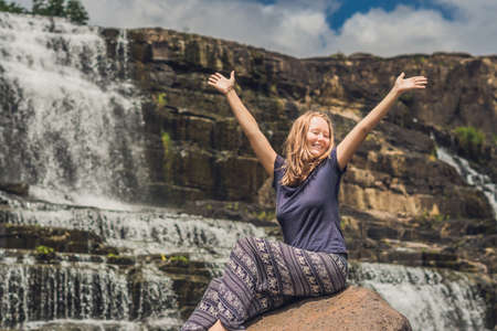 Young woman hiker, tourist on the background of Amazing Pongour Waterfall is famous and most beautiful of fall in Vietnam. Not far from Dalat city estimate 45 Km. Dalat, Vietnam.の写真素材