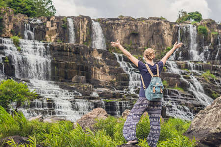 Young woman hiker, tourist on the background of Amazing Pongour Waterfall is famous and most beautiful of fall in Vietnam. Not far from Dalat city estimate 45 Km. Dalat, Vietnam.の写真素材