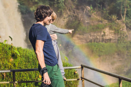 Father and son on the background of Majestic landscape of Elephant waterfall in summer at Lam Dong Province, Dalat, Vietnam. Look at the rainbow.の写真素材
