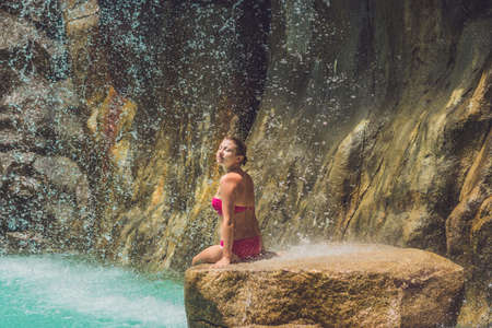 Young woman relaxing under a waterfall in aquapark. Vacation conceptの写真素材