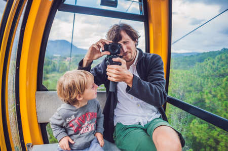 Father and son in ski lift cabin in summer. Passengers on a cable car.の写真素材