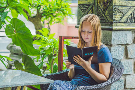 Beautiful woman ordering from menu in restaurant and deciding what to eat.の写真素材
