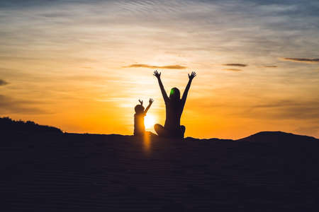 Fit mother with son running at the desert in Gran Canaria, Maspalomas on sunset.