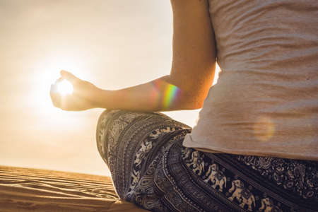 young woman meditating in rad sandy desert at sunset or dawn