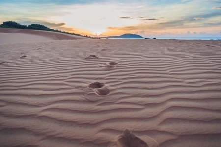 Footprints in the sand in the red desert at Sunrise.の写真素材