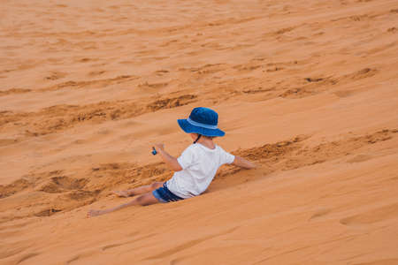 The boy in the red desert at dawn. Traveling with children concept.の写真素材