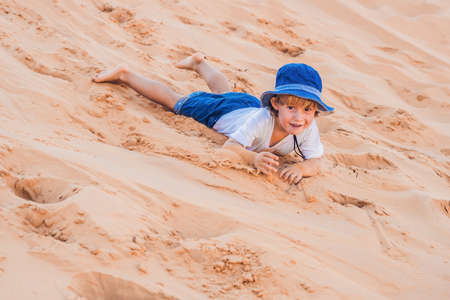 The boy in the red desert at dawn. Traveling with children concept.の写真素材