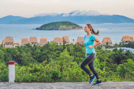 A sportive young woman is engaged in running against the sea.の写真素材