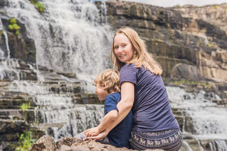 Mother and son hikers, tourists on the background of Amazing Pongour Waterfall is famous and most beautiful of fall in Vietnam. Not far from Dalat city estimate 45 Km. Dalat, Vietnam.の写真素材