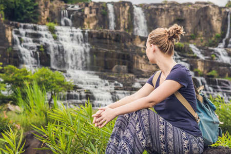 Young woman hiker, tourist on the background of Amazing Pongour Waterfall is famous and most beautiful of fall in Vietnam. Not far from Dalat city estimate 45 Km. Dalat, Vietnam.の写真素材