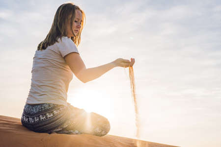 young woman in rad sandy desert at sunset or dawnの写真素材