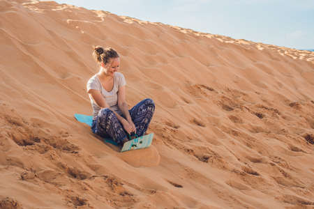 Young woman rolls on a toboggan in the sledge in the desert.の写真素材
