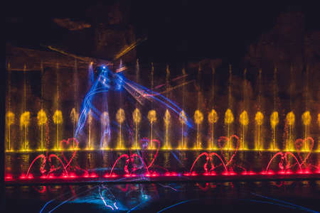 Multicolored dancing water jet fountain in the dark.の写真素材