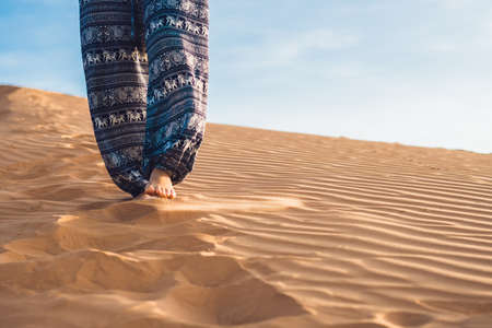 young woman in rad sandy desert at sunset or dawnの写真素材