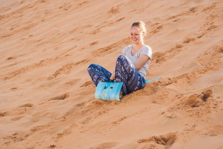 Young woman rolls on a toboggan in the sledge in the desert.の写真素材