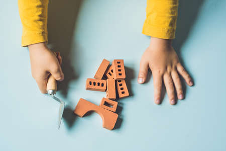 Close up of child's hands playing with real small clay bricks at the table. Toddler having fun and building out of real small clay bricks. Early learning. Developing toys. Construction concept.の写真素材