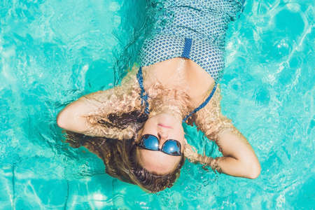 Beautiful young woman floating in pool relaxing Top view. Holiday concept.の写真素材