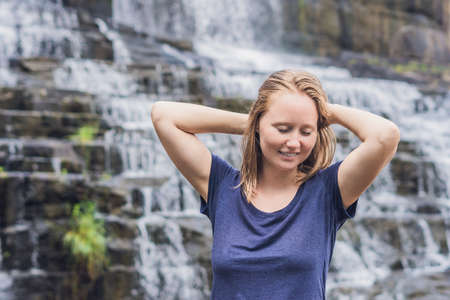 Young woman hiker, tourist on the background of Amazing Pongour Waterfall is famous and most...