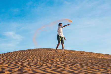 A man is kicking sand in a red desert. Splash of anger concept.の写真素材