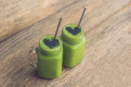 Fresh green smoothie with banana and spinach with heart of sesame seeds. Love for a healthy raw food concept.の写真素材
