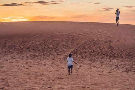 Father and son at the red desert at dawn. Traveling with children concept.の写真素材