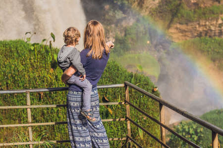 Mom and son on the background of Majestic landscape of Elephant waterfall in summer at Lam Dong Province, Dalat, Vietnam. Look at the rainbow.の写真素材