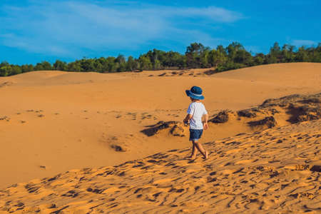 The boy in the red desert at dawn. Traveling with children concept.の写真素材