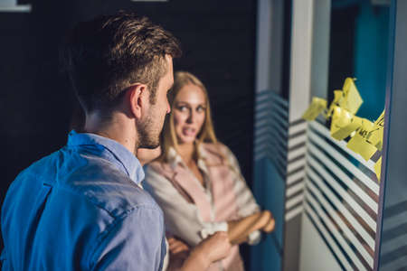 Three businesspeople discussing and planning concept. Front of glass wall marker and stickers....