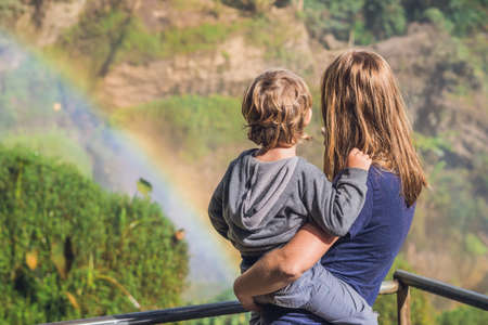 Mom and son on the background of Majestic landscape of Elephant waterfall in summer at Lam Dong Province, Dalat, Vietnam. Look at the rainbow.の写真素材