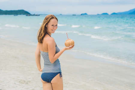 Young woman drinking coconut milk on beach. Dream scape Escape with beauty girl. The Benefits of Coconut Water.の写真素材