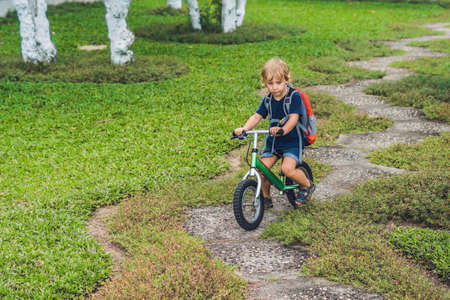 Little boy on a balance bike. Caught in motion, on a driveway. Preschool child's first day on the bike. The joy of movement. Little athlete learns to keep balance while riding a bicycle.の写真素材