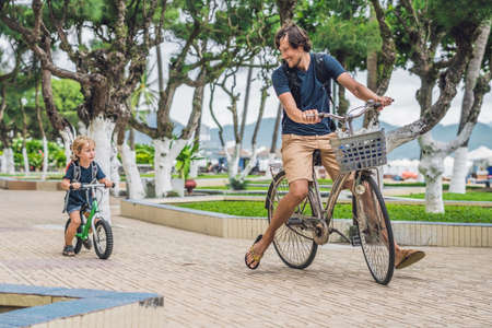 Happy family is riding bikes outdoors and smiling. Father on a bike and son on a balancebike.