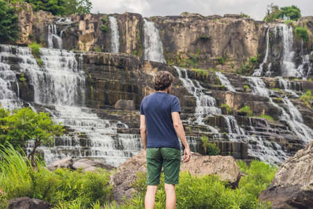 Man hiker, tourist on the background of Amazing Pongour Waterfall is famous and most beautiful of fall in Vietnam. Not far from Dalat city estimate 45 Km. Dalat, Vietnam.の写真素材