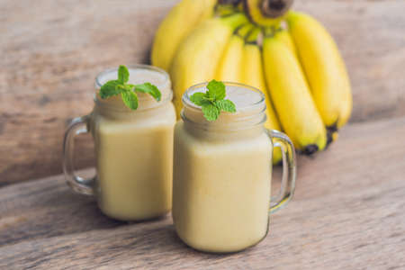 Banana smoothies and bananas on an old wooden background.の写真素材