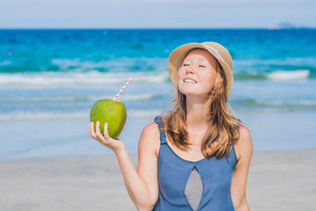 Attractive young woman drinking coconut water on the beach.の写真素材
