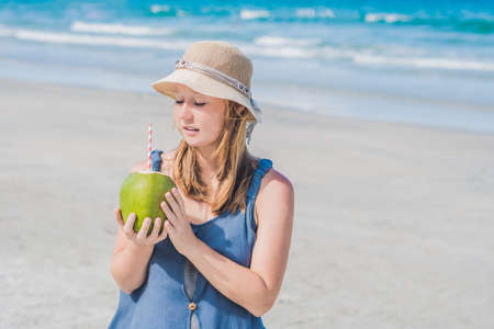 Attractive young woman drinking coconut water on the beach.の写真素材