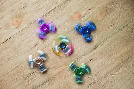 Colored fidget spinners stress relieving toy on wooden background.の写真素材