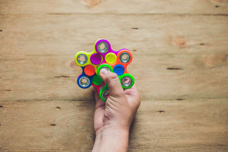 A man hand holding hand spinner or fidget spinner over wooden background.の写真素材