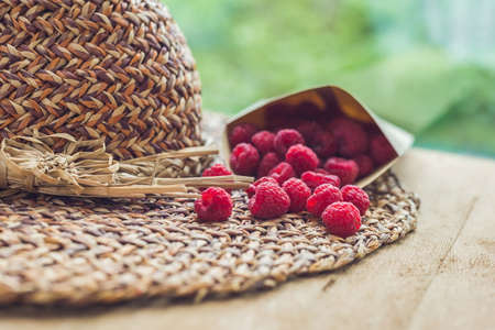 Summer holiday, vacation, relaxation concept. Raspberries, straw hat, on wooden background. Free...