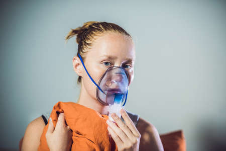 Woman with flu or cold symptoms making inhalation with nebulizer - medical inhalation therapy.の写真素材
