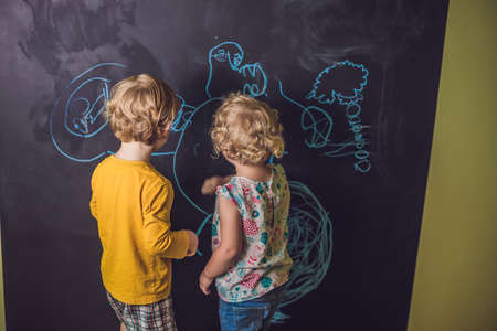 Boy and girl paint with chalk on a blackboard.の写真素材