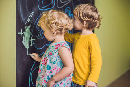 Boy and girl paint with chalk on a blackboard.の写真素材