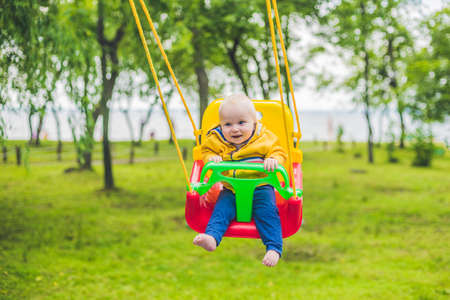 happy little boy riding on a swing in a park.の写真素材
