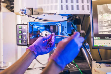 Scientist in a laboratory works with an electron microscope gateway. Putting a sample into a chamber.の写真素材