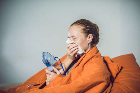 Woman with flu or cold symptoms making inhalation with nebulizer - medical inhalation therapy.の写真素材