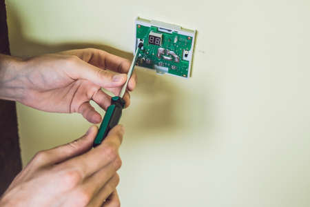 Electrician installing an electrical thermostat in a new house.の写真素材
