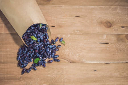 Fresh honeysuckle blue berry fruits with leaf on a wooden background.の写真素材