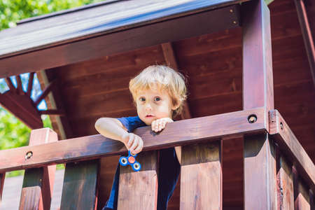 Boy playing with fidget spinner. Child spinning spinner on the playground. Blurred background.の写真素材