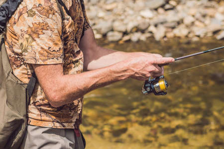 Man fishing on a mountain river with a ultralight spinning using fishing wobblers. He got his hook hooked for something.の写真素材
